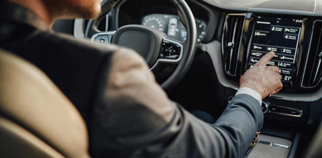 Driver in a suit interacts with a car’s touchscreen while driving, highlighting the role of technology in Uber and Lyft accidents requiring a lawyer in Las Vegas