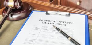Personal injury claim form with pen and gavel on desk, representing legal case documentation and filing