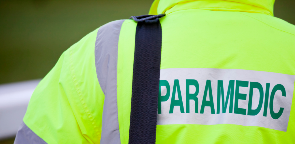 Close-up of a paramedic's neon jacket with PARAMEDIC printed in bold green letters on the back