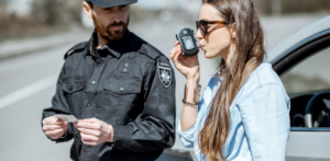 Police officer holds a license while a woman blows into a breathalyzer during a roadside DUI test