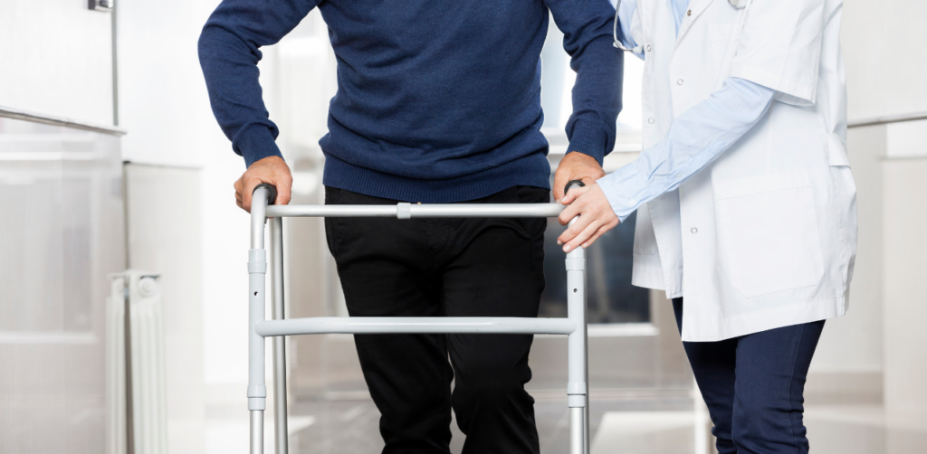 Healthcare professional assisting a man using a walker in a hospital hallway