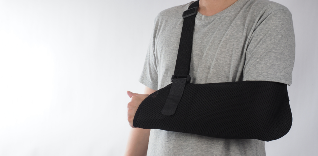 Person in a gray shirt wearing a black arm sling, indicating an arm or shoulder injury