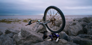 Damaged bicycle flipped upside down on rocky terrain near the coast, symbolizing serious accidents that may require a bike accident lawyer