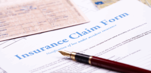 Close-up of an “Insurance Claim Form” partially covered by a fountain pen and an ID card, representing the process of filing a claim after an accident