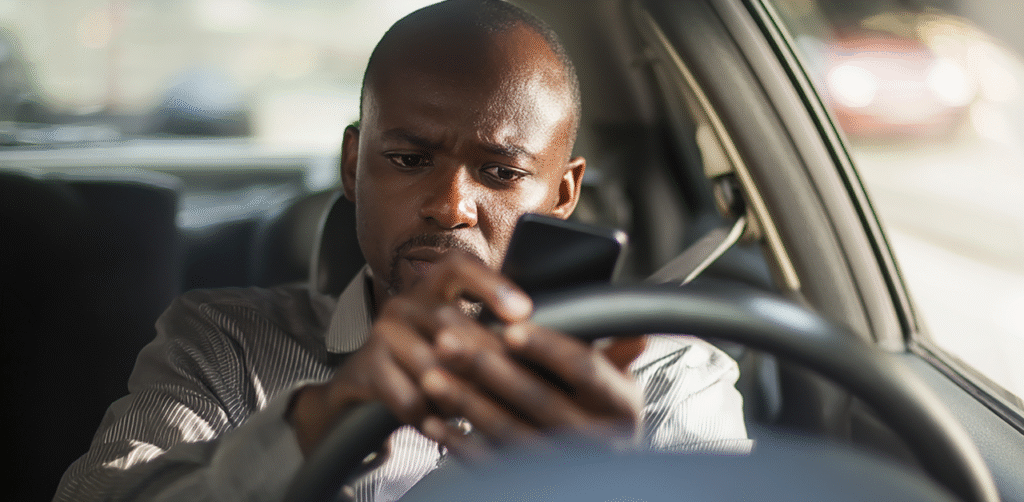 Man texting on smartphone while driving car, distracted driving risk