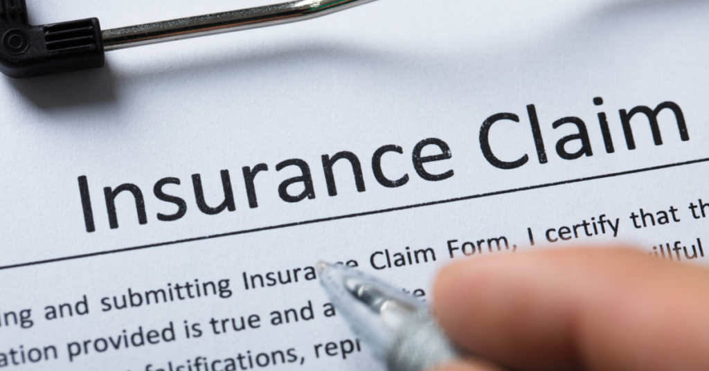 A close-up of an insurance claim form with a pen hovering above it, ready to fill in details