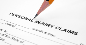 A pencil points toward the words "Personal Injury Claims" on a document, suggesting a form to file for compensation after an accident