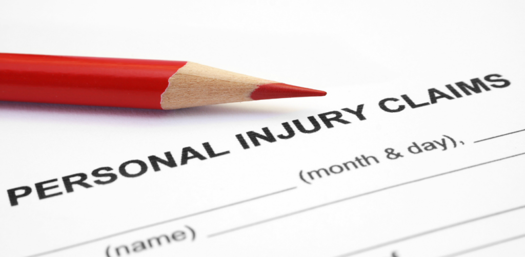 A close-up of a red pencil placed on top of a form labeled Personal Injury Claims, partially filled in