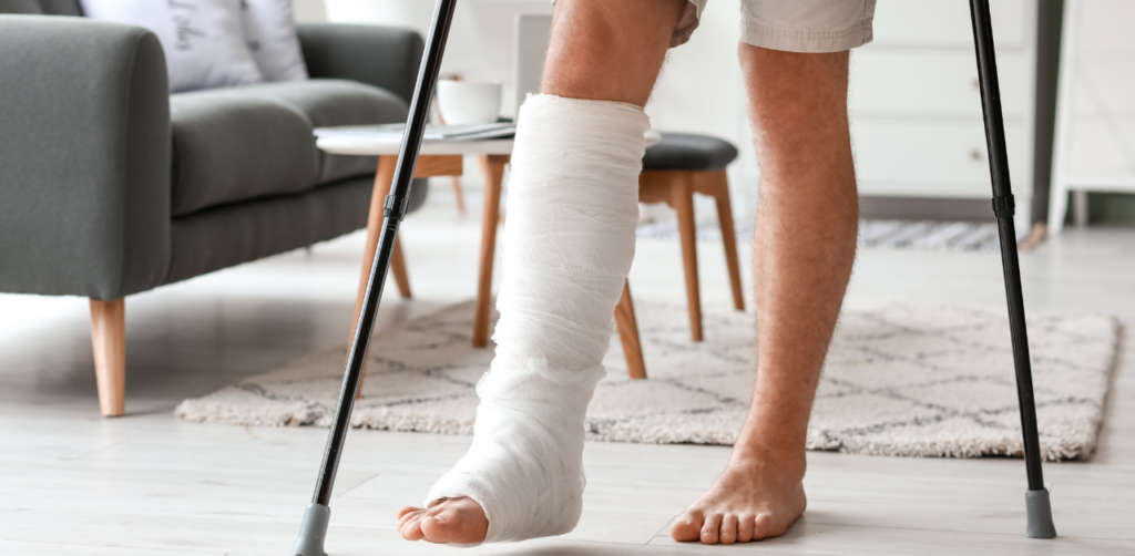 Close-up of a person’s leg in a cast, standing with crutches in a modern living room