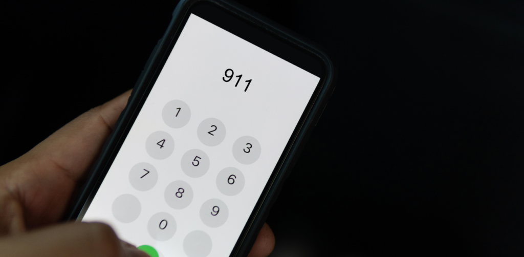 Hand holding a smartphone with 911 dialed on the screen, ready to make an emergency call