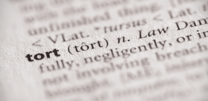 Close-up of the word tort in a dictionary, with its pronunciation and legal definition in focus