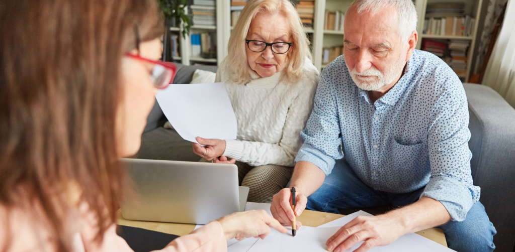 Elderly couple reviewing documents with a professional, in what appears to be a consultation or signing session