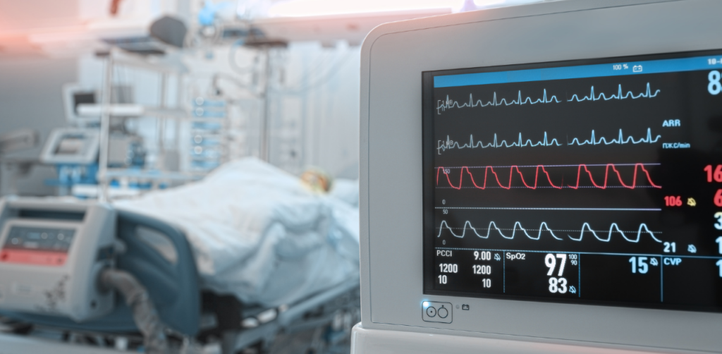 Hospital room with a patient bed in the background and a monitor displaying vital signs in the foreground