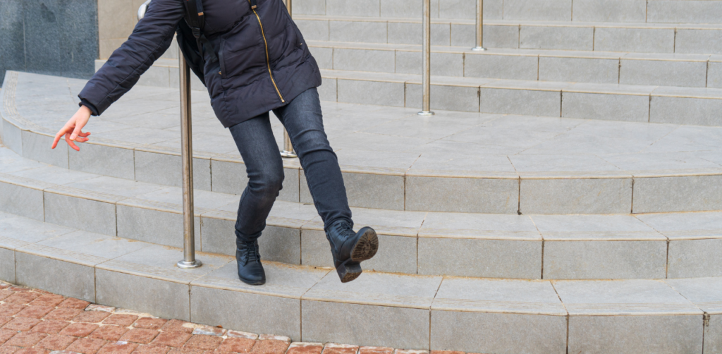 Person losing balance on a staircase, holding onto a railing