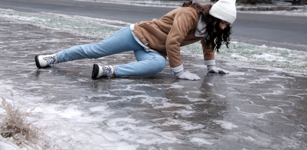 Woman in winter clothing slipping on an icy sidewalk