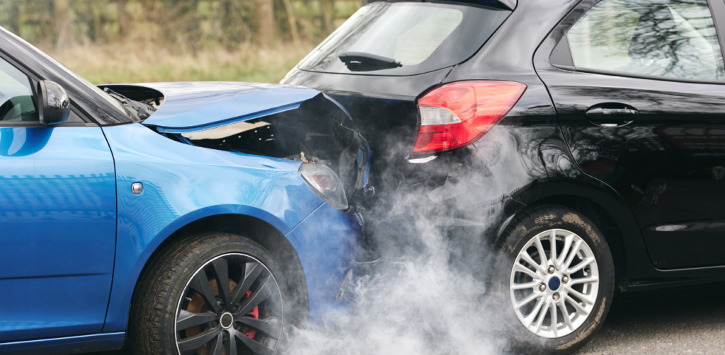 A damaged blue car with a crumpled hood after rear-ending a black vehicle, with smoke rising from the impact