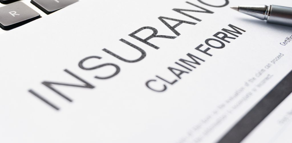 Close-up of an insurance claim form with a pen resting on it, ready for completion