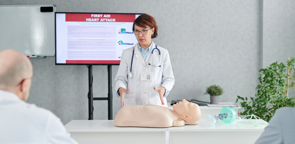 Doctor demonstrating CPR on a mannequin during a first aid training class on heart attack response