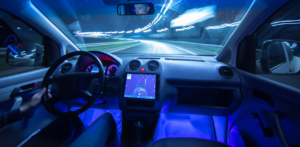 Night view from inside a self-driving car, with a glowing dashboard and navigation screen active
