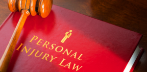 Wooden gavel resting on a red legal book titled Personal Injury Law in gold letters