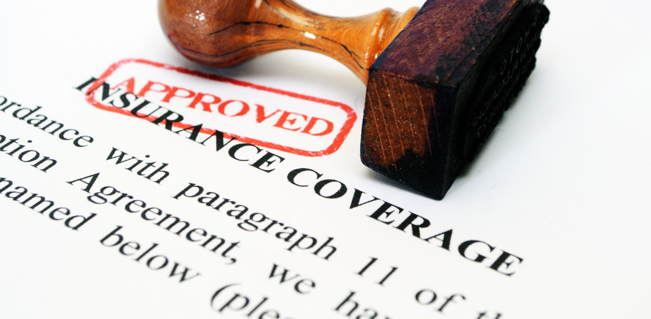 Wooden stamp marked “APPROVED” on an insurance coverage form, confirming document approval