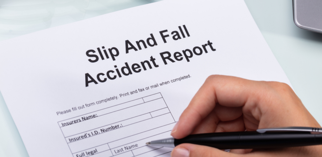 Hand holding a pen over a slip and fall accident report form, ready to fill in details after an injury incident