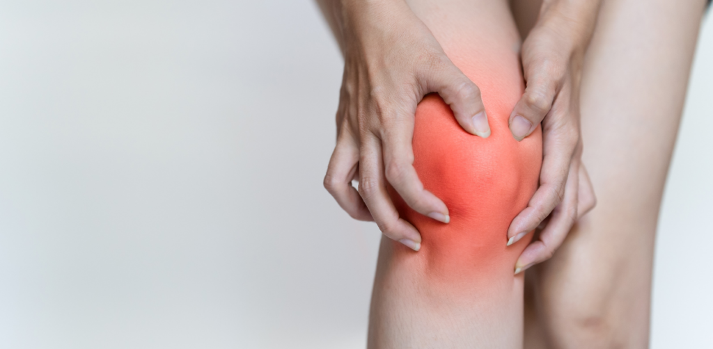 Person clutching a red, inflamed knee in pain, indicating possible joint injury or arthritis