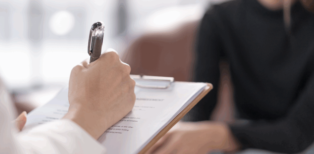 Close-up of a therapist writing notes on a clipboard during a counseling session