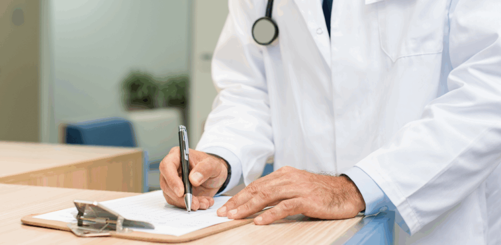 Doctor in white coat writing notes on a clipboard at a medical office reception desk