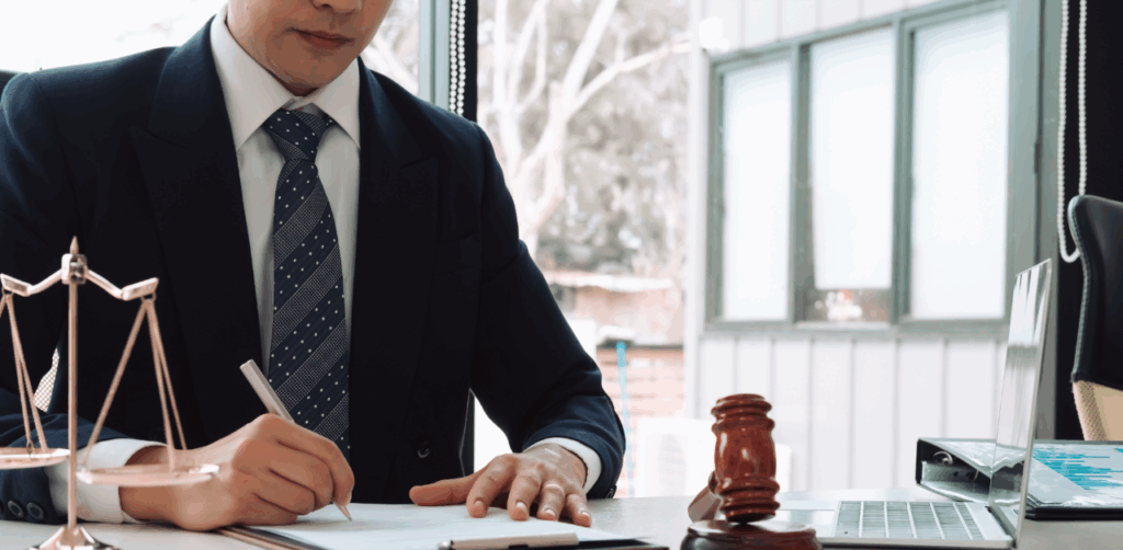 Lawyer in a suit writing at a desk with legal scales and a gavel nearby