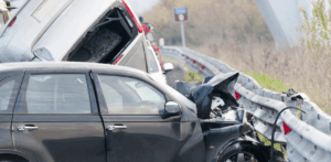 A black car crashes into a guardrail in a severe highway accident involving multiple vehicles
