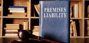 Large blue legal book titled “Premises Liability” stands upright beside a wooden gavel in a law library, symbolizing legal issues related to property safety and responsibility