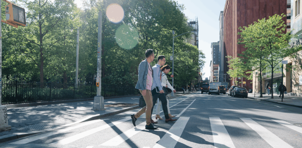 People crossing a city street in daylight, highlighting urban crosswalks and pedestrian safety