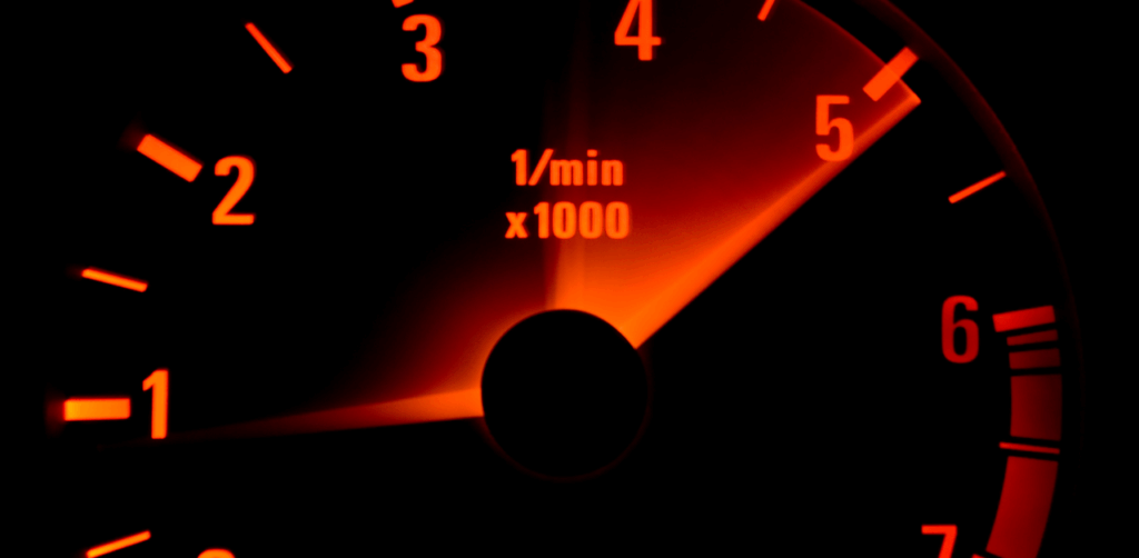 Close-up of illuminated tachometer needle pointing near 5,000 RPM