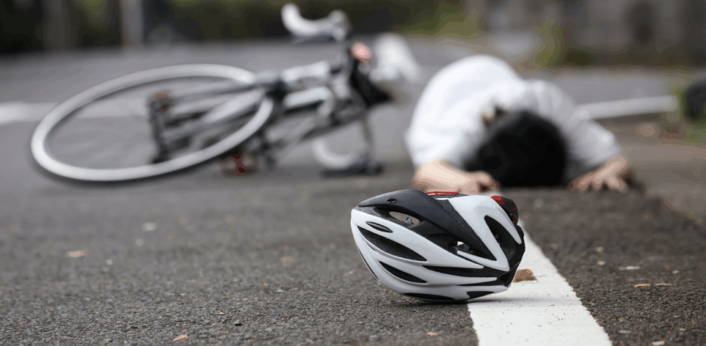 Cyclist lies injured on road near fallen bike and helmet after accident