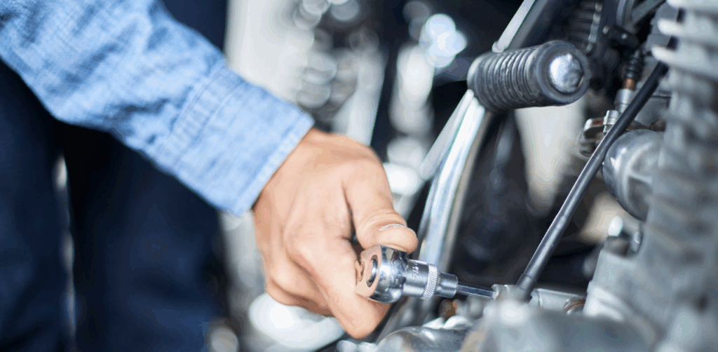 Mechanic’s hand tightens bolt on motorcycle with a ratchet tool