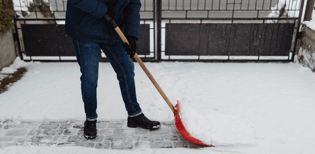 Person shoveling snow from driveway during winter to clear a safe path