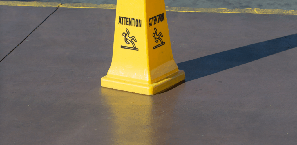 Yellow caution cone on smooth surface warns of slip and fall hazard