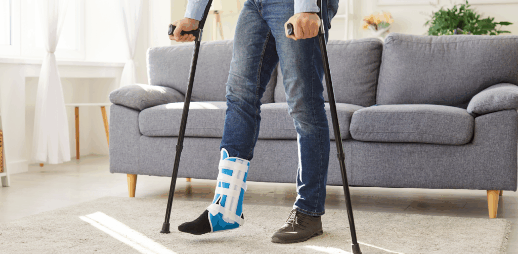Person using crutches and a medical boot after a leg injury at home