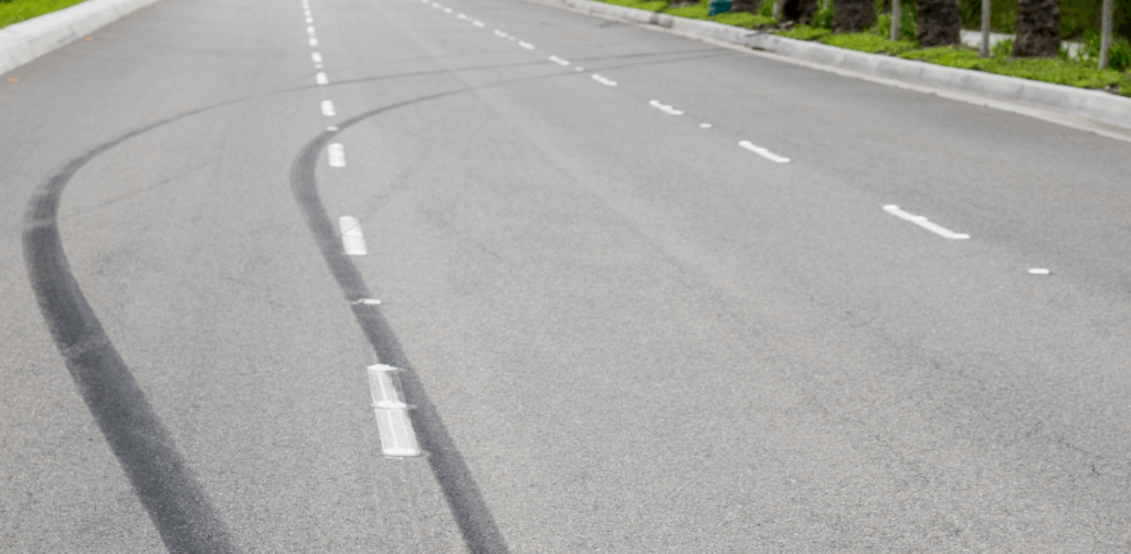 Skid marks curve across empty lanes on a paved road after sudden braking