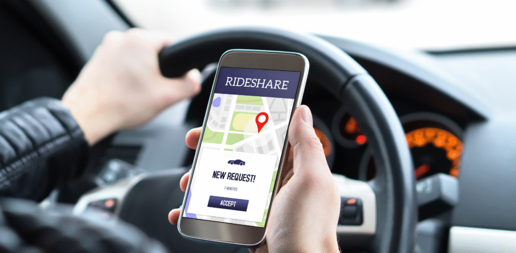 Driver holding smartphone with rideshare app showing new ride request while steering car, highlighting distracted driving risk