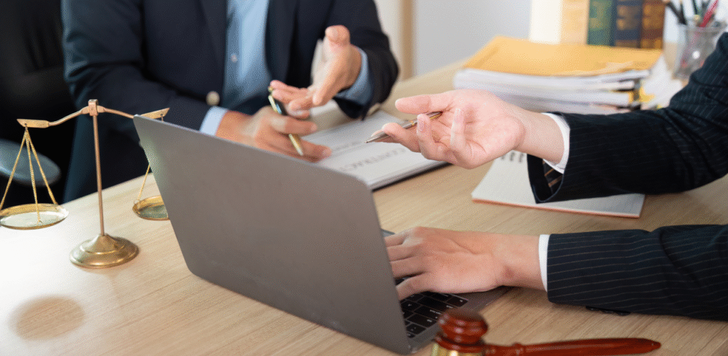 Lawyers discussing case over laptop with scales of justice and gavel on desk, representing legal consultation