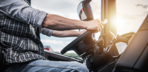 Truck driver gripping steering wheel inside cab, representing commercial driving, transportation industry, and road safety