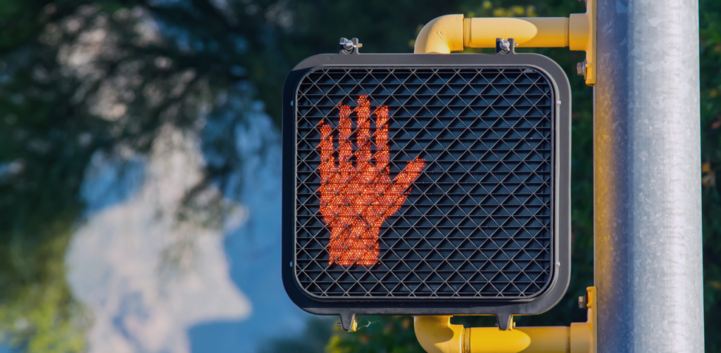 Pedestrian crossing signal displays a red hand, indicating pedestrians should wait