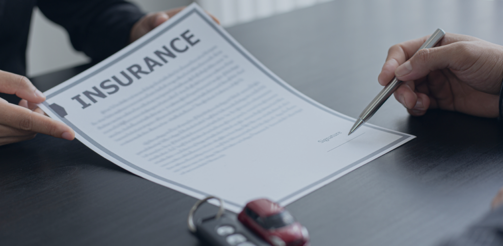 Person points to the signature line on an insurance document beside car keys