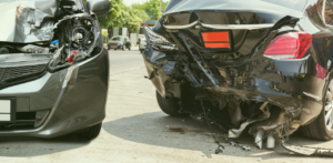 Two cars with severe front and rear-end damage after a collision, parked on a roadway